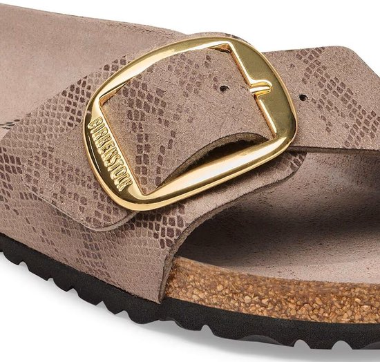 Gros plan sur la grande boucle dorée d'une sandale Birkenstock taupe à imprimé python.