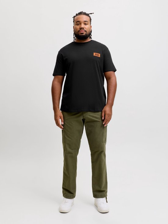 Model in zwart T-shirt met oranje label op de borst en legergroene cargo broek.