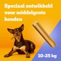 Kleine bruine hond kauwt op een Dentastix. "Speciaal ontwikkeld voor middelgrote honden", 10-25 kg.