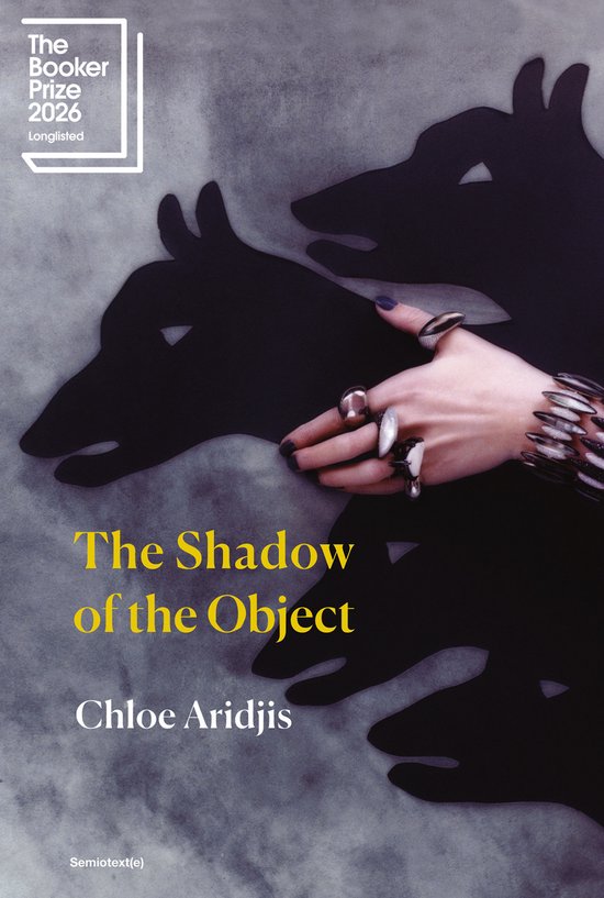 Boek "The Shadow of the Object" door Chloe Aridjis, genomineerd voor de Booker Prize 2026. Met schaduwen van honden en een hand met ringen.