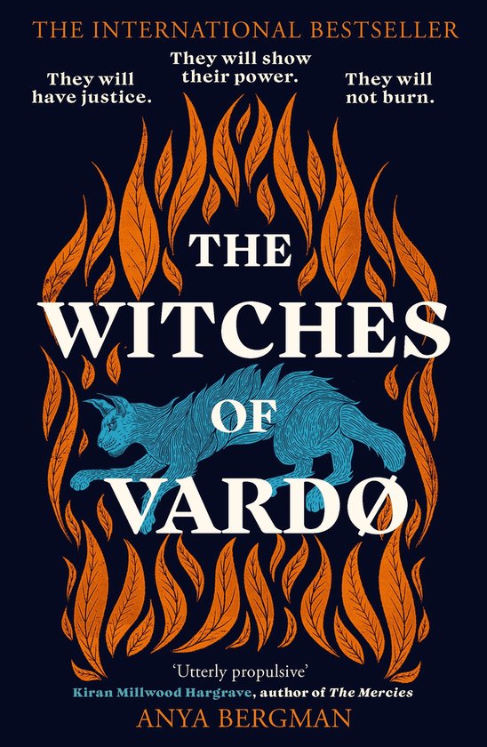 Boek "The Witches of Vardo" met een blauwe kat op een donkerblauwe achtergrond, omringd door oranje vlammen en bladeren. Tekst: "THE WITCHES OF VARDO".