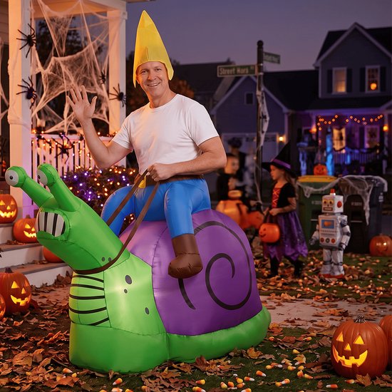 Een man in een opblaasbaar slakkenkostuum met gele muts, zwaaiend bij een versierd Halloween-huis.