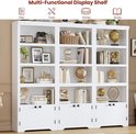 Brede witte boekenkast met 3 secties, elk met 4 open planken en 2 gesloten deuren onderaan. Gevuld met boeken en decoraties.