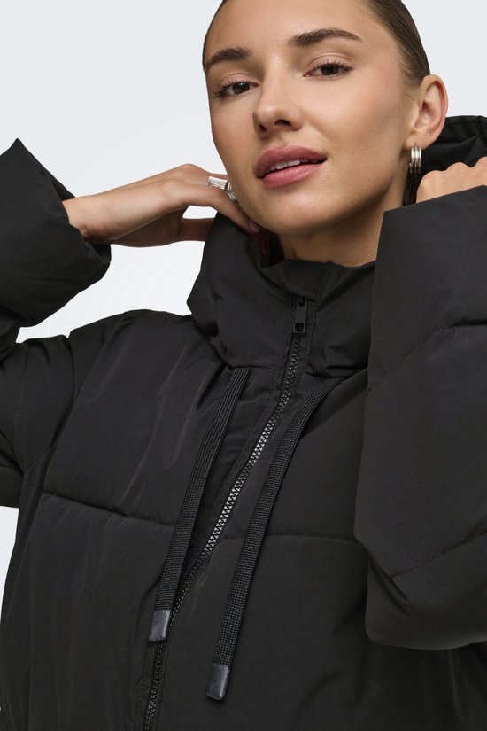 Model met zwarte pufferjas met hoge kraag en trekkoorden.