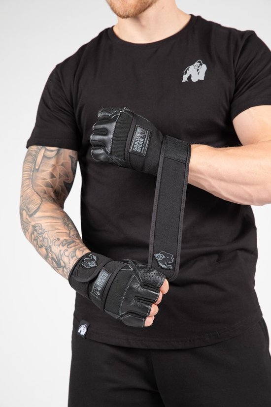 Man met getatoeëerde armen draagt zwarte Gorilla Wear Dallas polsbandage handschoenen.