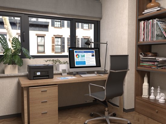 Zwarte Epson printer staat op een bureau naast een computer en planten, in een kantoor aan huis.