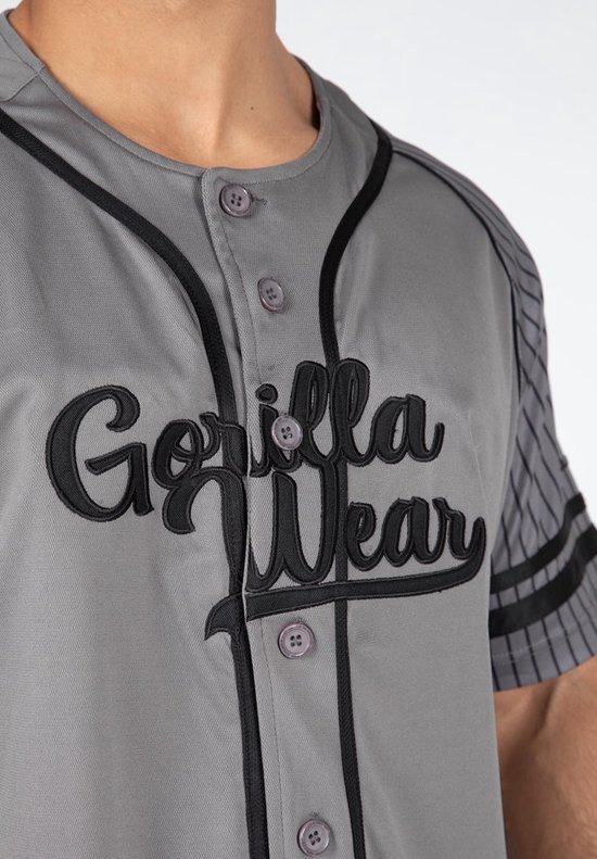 Close-up van een grijze baseball jersey met zwarte opdruk 'Gorilla Wear' en gestreepte mouwen.