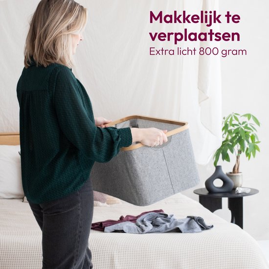 Vrouw met grijze wasmand met bamboe rand in slaapkamer.