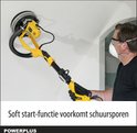 Man met gele en zwarte schuurmachine met lange steel die een plafond schuurt.
