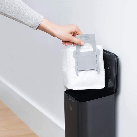 Hand plaatst witte stofzak in zwarte iRobot Roomba i3 zelflegende basis.