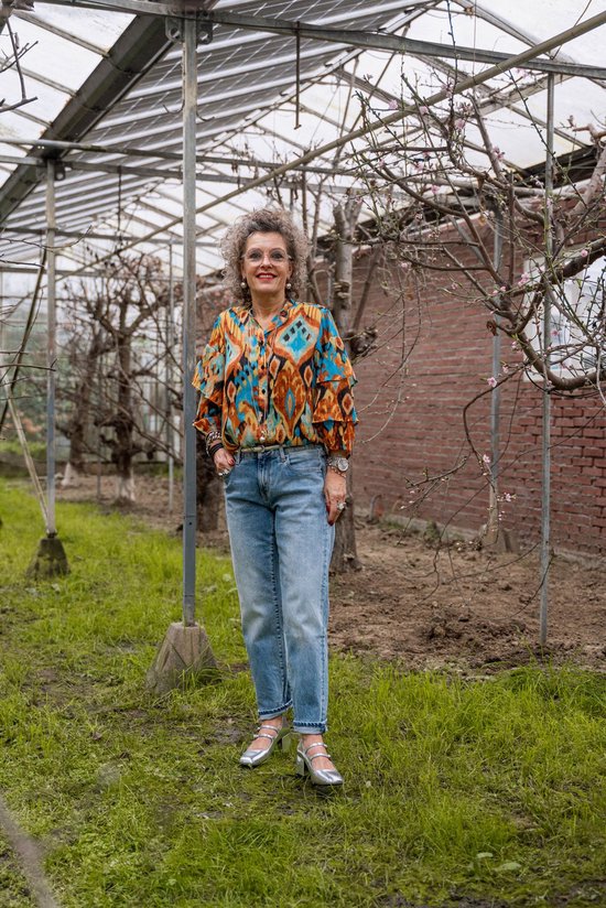Model draagt een wijde, lichtblauwe jeans en een kleurrijk shirt met geometrisch patroon.