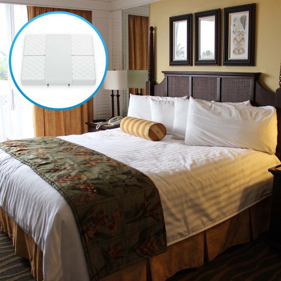Luxe hotelkamer met een groot bed met gestreepte lakens, groen bloemenbedloper, en een detail van de matraswig.