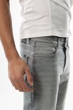 Close-up van een man in een grijze jeans en een witte T-shirt met "CARS" logo op de tailleband.