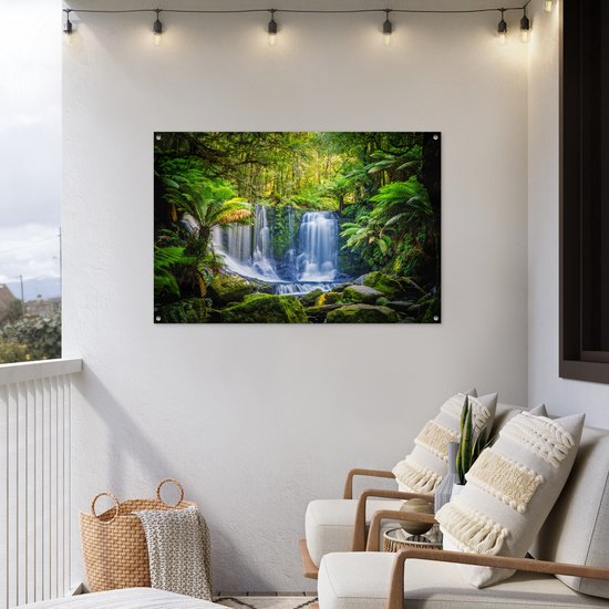 Waterval in een groen bos, met varens en mos, op een wit balkon.