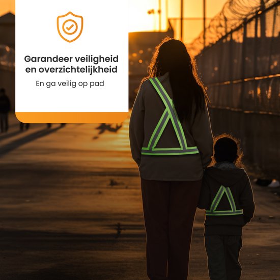 Moeder en kind lopen over een pad bij zonsondergang, beiden dragen een reflecterend sportvest.