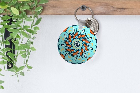 Porte-clés - motif sur fond bleu clair avec une fleur orange et des décorations - Plastique - Rond