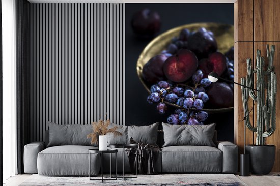 Behang - Fotobehang Gouden kom met paarse druiven in het donker - Breedte 225 cm x hoogte 350 cm