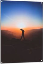 WallClassics - Tuinposter – Silhouet Persoon tussen de Bergen bij Zonsondergang - 80x120 cm Foto op Tuinposter (wanddecoratie voor buiten en binnen)
