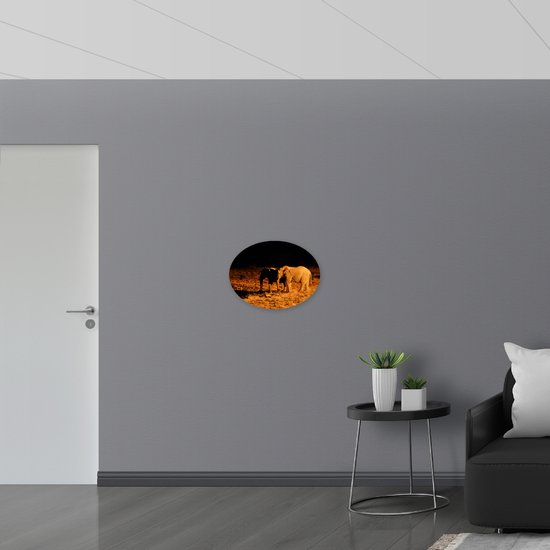 PVC Schuimplaat Ovaal - Twee Olifanten in het Landschap tijdens de Donkere Nacht - 56x42 cm Foto op Ovaal (Met Ophangsysteem)