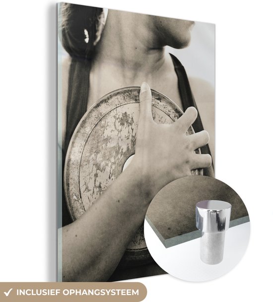 MuchoWow® Glasschilderij 30x40 cm - Schilderij acrylglas - Zwart-wit foto van een vrouw met een discus in haar hand - Foto op glas - Schilderijen