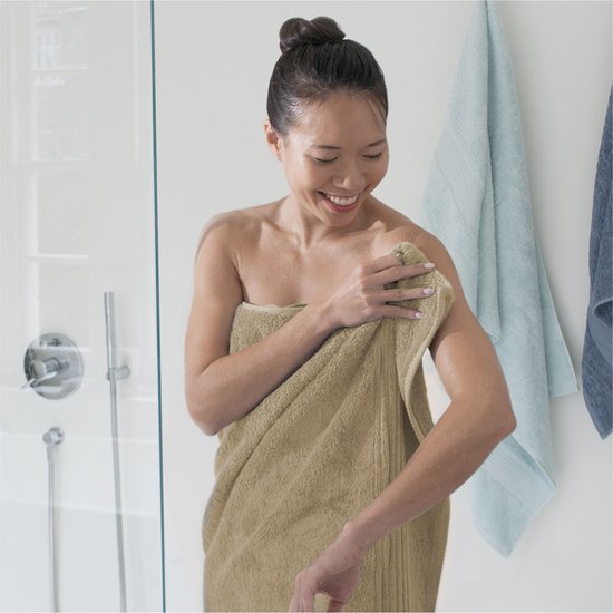 Vrouw met een handdoek om, lachend na het douchen, met waterdruppels op de huid.