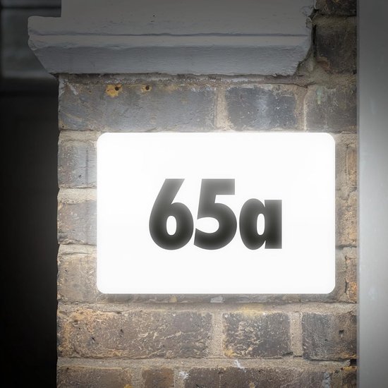Verlicht huisnummer '65a' op een bakstenen muur.