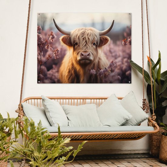 Tuinposter met Schotse hooglander met bloemen, boven een schommelbank aan een witte muur.