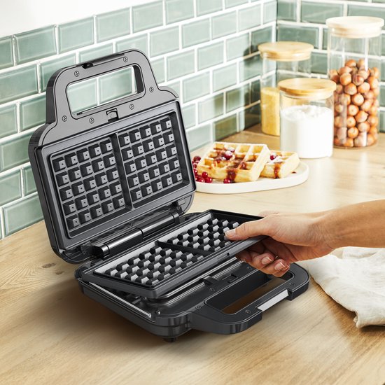 Hand wisselt een wafelplaat om in een open Tefal wafelijzer.