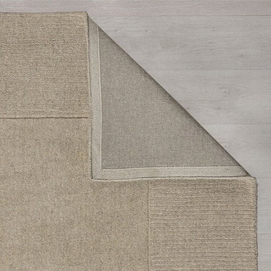 Onderkant van een lichtbeige vloerkleed, met een subtiel kader en textuurverschil.