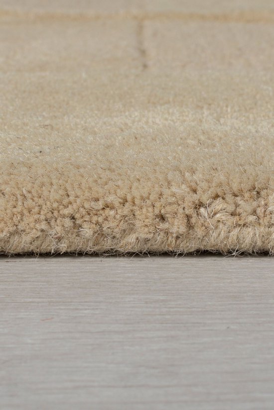 Close-up van een beige vloerkleed met een gedempte textuur en subtiele lijnen.
