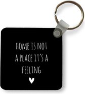 Sleutelhanger - Uitdeelcadeautjes - Engelse quote Home is not a place it's a feeling met een hartje tegen een zwarte achtergrond - Plastic