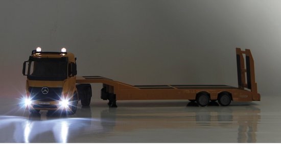 Gele Mercedes-Benz Arocs dieplader speelgoed vrachtwagen met koplampen aan.