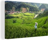 Canvas Schilderij Vrouw staat in een rijstveld in Indonesië - 60x40 cm - Wanddecoratie