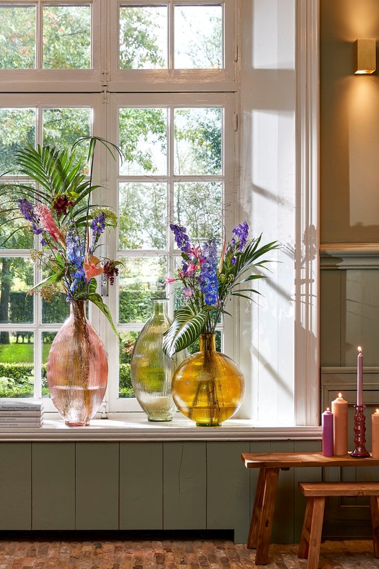Rustieke houten bank met decoratieve vazen en bloemen, bij een venster.