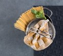 Kookmat in antraciet met een pan vol spaghetti, een takje basilicum en een mosterdgele handdoek.