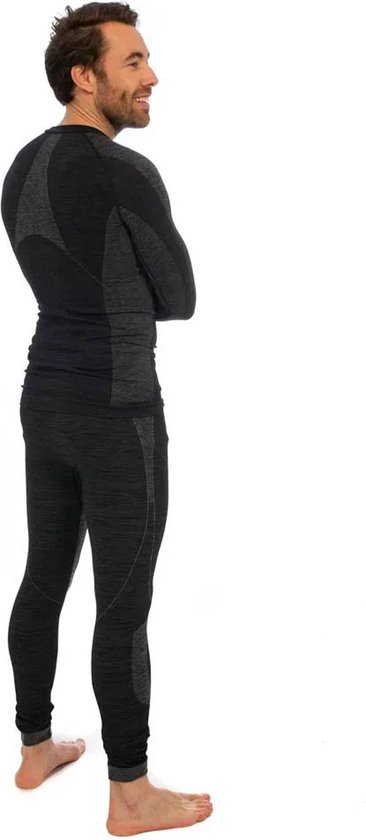 Man staat in profiel in een zwarte en grijs gemêleerde thermo set, met gekruiste armen. Het shirt heeft een hoge kraag, de legging loopt tot de enkels.