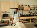 Man met een schort die naar een e-reader kijkt die op een met bloem bestoven tafel ligt.