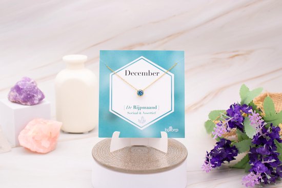 Gouden ketting met blauwe zirkonia op kaart met "December".