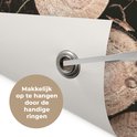 Détail d'une affiche de jardin avec des bûches empilées. Un œillet en métal pour la suspension est visible. Texte 'Facile à accrocher grâce aux œillets pratiques'.