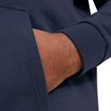 Close-up van een hand die in de zak van een donkerblauwe hoodie wordt gestopt.