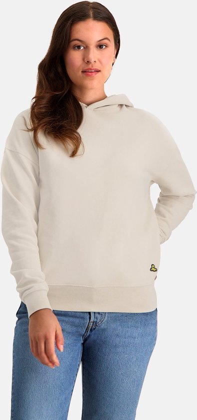 Vrouw draagt een losvallende ecru hoodie, met gele applicatie, en jeans.
