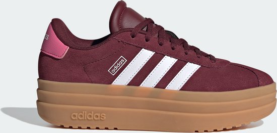 Bordeauxrode Adidas sneakers met witte strepen en een dikke bruine zool.