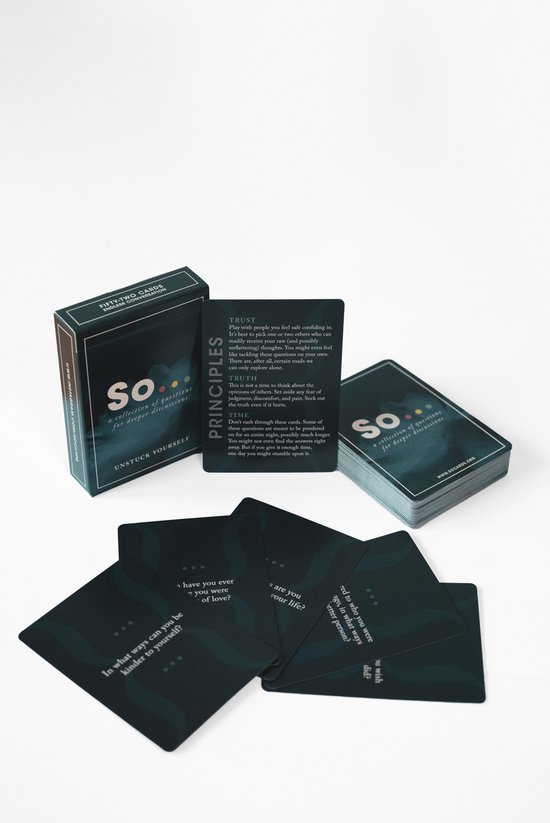 Een open doos 'So... a collection of questions for deeper discussions' met principes en een stapel kaarten. Kaarten hebben witte tekst en stippen.