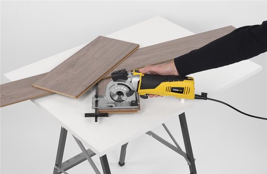 Gele met zwarte mini invalzaag met laser, in gebruik bij het zagen van laminaatplaten op een werktafel.