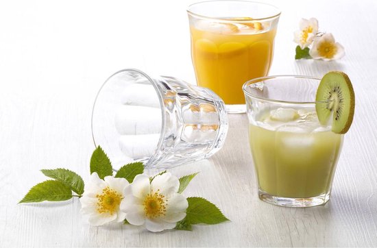 Trois verres, deux remplis de jus. Un verre vide repose sur le côté. Avec des fleurs et des feuilles vertes.