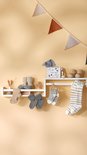 Muurschap met babyproducten: slabbetjes, sokjes, speelgoed en decoratie. Ook sokjes met strepen en sterretjes.