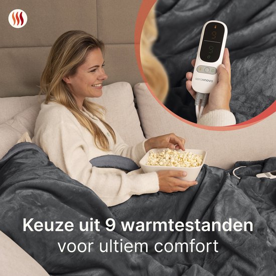 Vrouw met een kom popcorn onder een grijze elektrische deken, genietend van de film. Keuze uit 9 warmtestanden voor ultiem comfort.