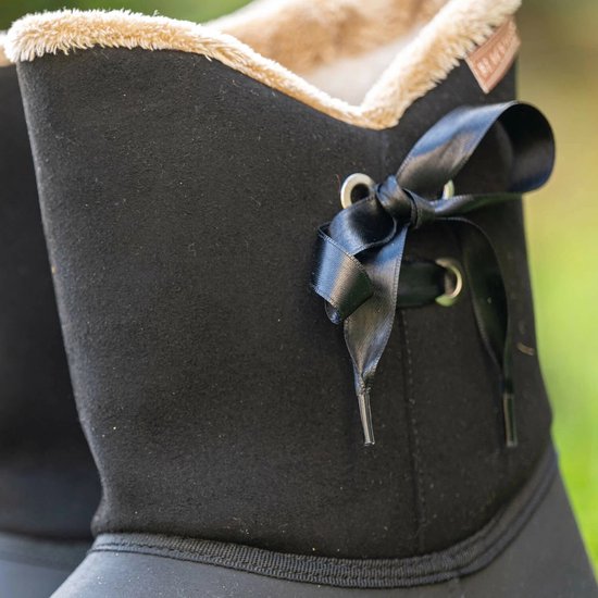 Close-up van zwarte laars met beige teddy voering en een zwart satijnen strikje.