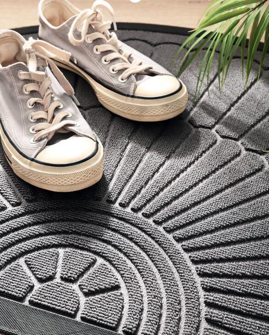 Close-up van grijze Converse sneakers op een halfronde deurmat met fan-patroon.