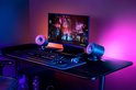 Gaming bureau met Razer speakers, toetsenbord, muis en monitor met paars/blauw licht.